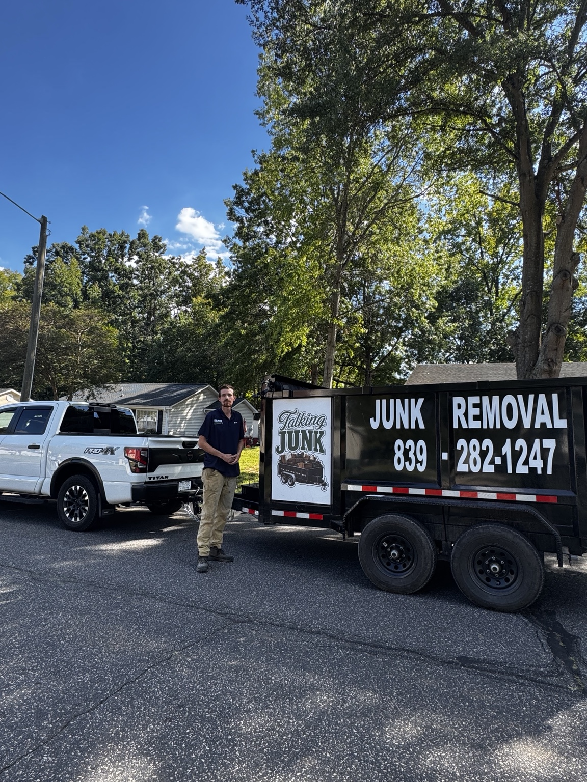 Talking Junk owner standing beside the company truck and junk removal trailer